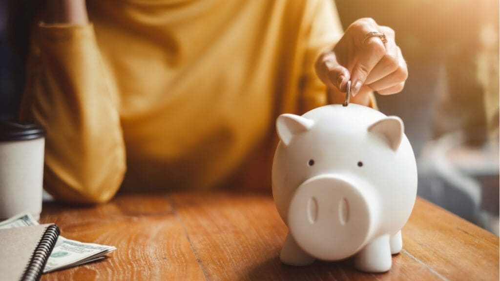 A woman depositing a coin into a piggy bank