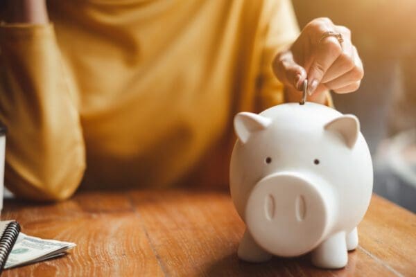 A woman depositing a coin into a piggy bank