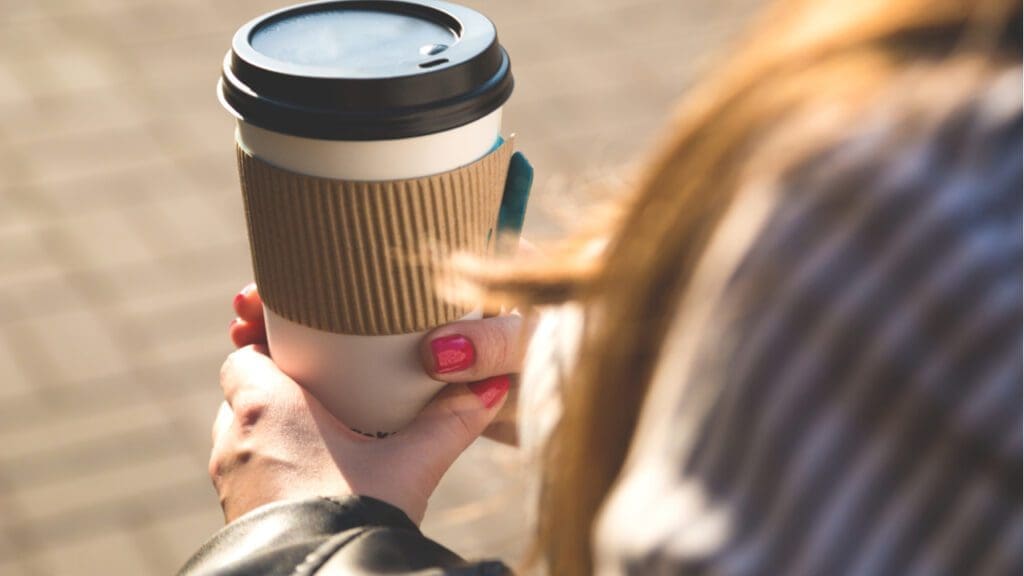 A woman holding a takeaway cup of coffee
