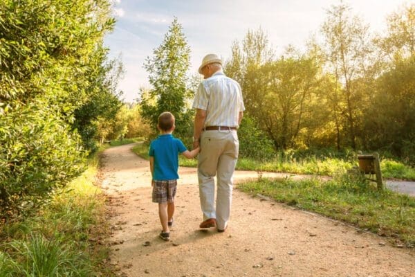 A grandfather and grandchild walking through a park